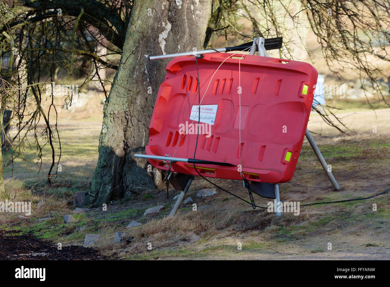 Karlshamn, Sweden - February 04, 2016: A red plastic lifeboat under a tree on a stand. This lifesaver is located at a public bat Stock Photo