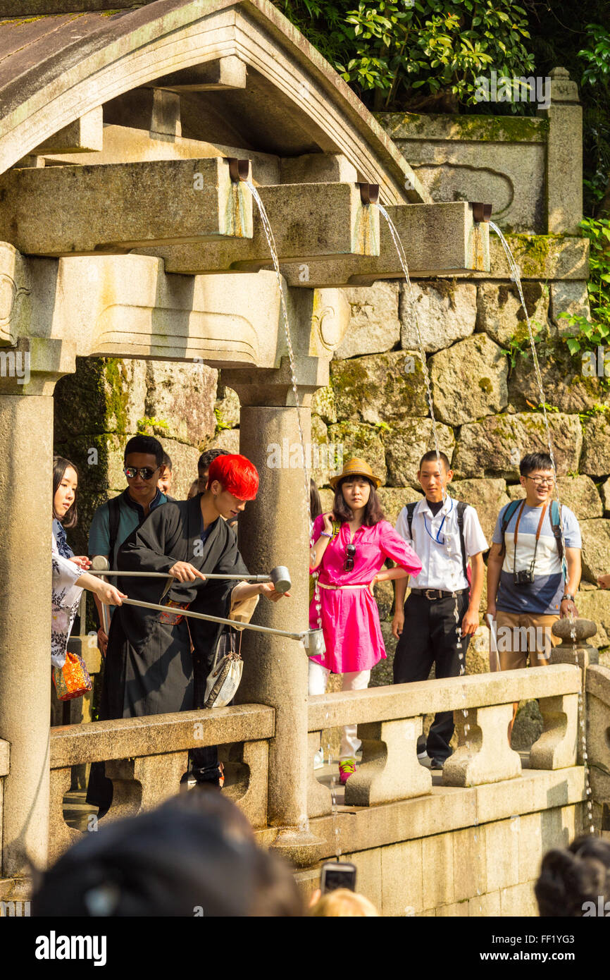 Tourists lining up at the base of Kiyomizu-dera temple to catch drinking water using cups with long pole handles at Otowa-no-ta Stock Photo