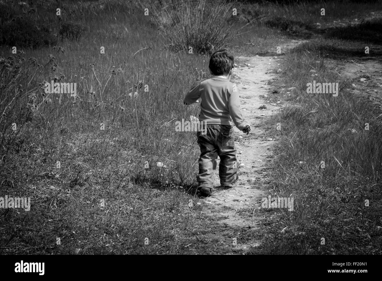 A one year old boy taking some of his first steps outdoors on a path