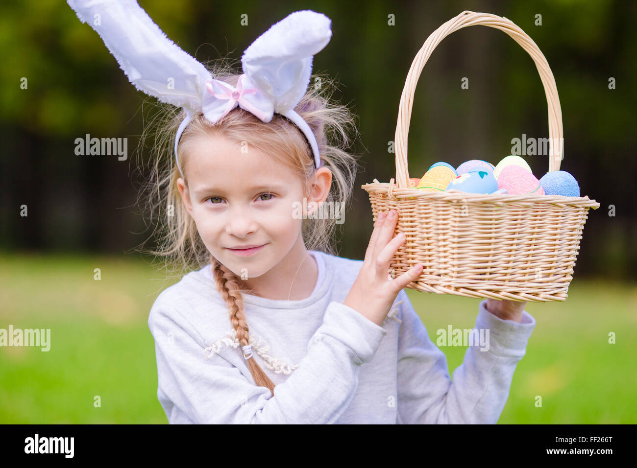 Cute little girl wearing bunny ears with a basket full of Easter eggs ...