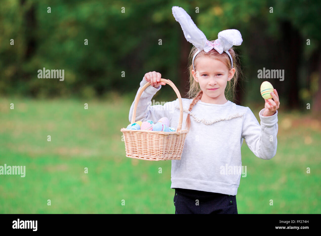 Adorable little girl wearing bunny ears holding a basket with Easter ...