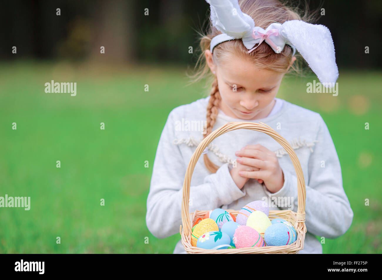 Cute little girl wearing bunny ears holding a basket with Easter eggs ...