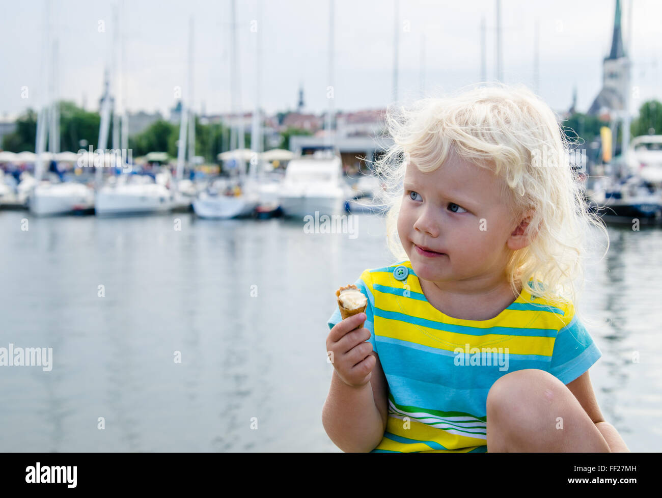 Little girl eating ice cream on a background of harbor Stock Photo