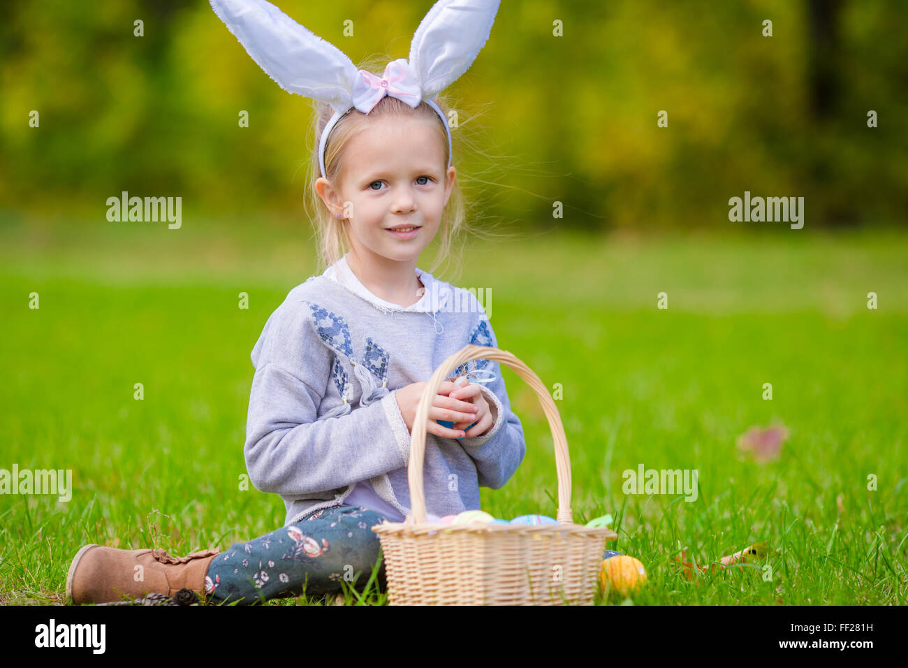 Adorable little girl wearing bunny ears with a basket full of Easter ...
