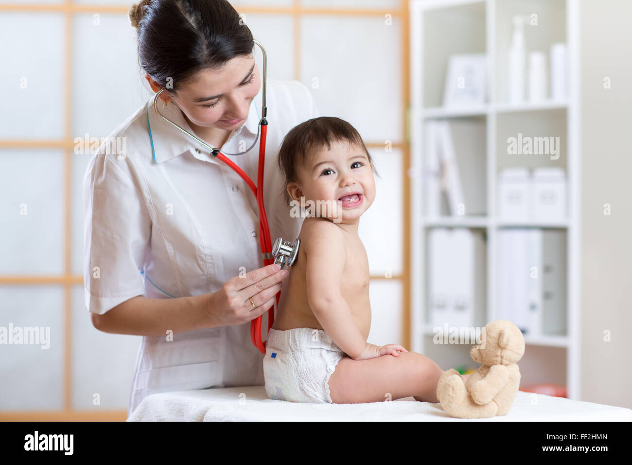 pediatrician doctor examining heartbeat of baby with stethoscope Stock Photo