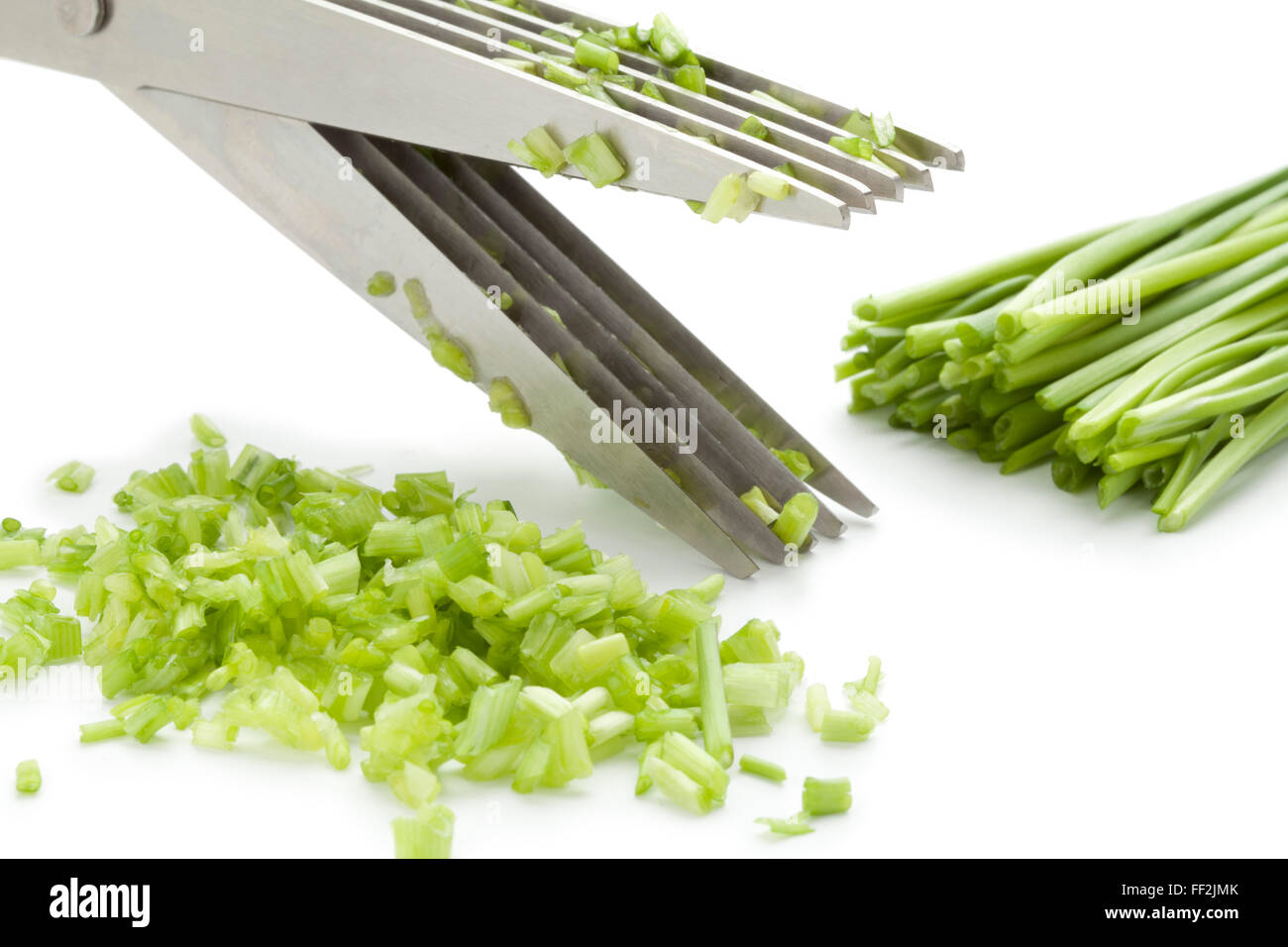 Herb scissors cutting fresh chives on white background Stock Photo