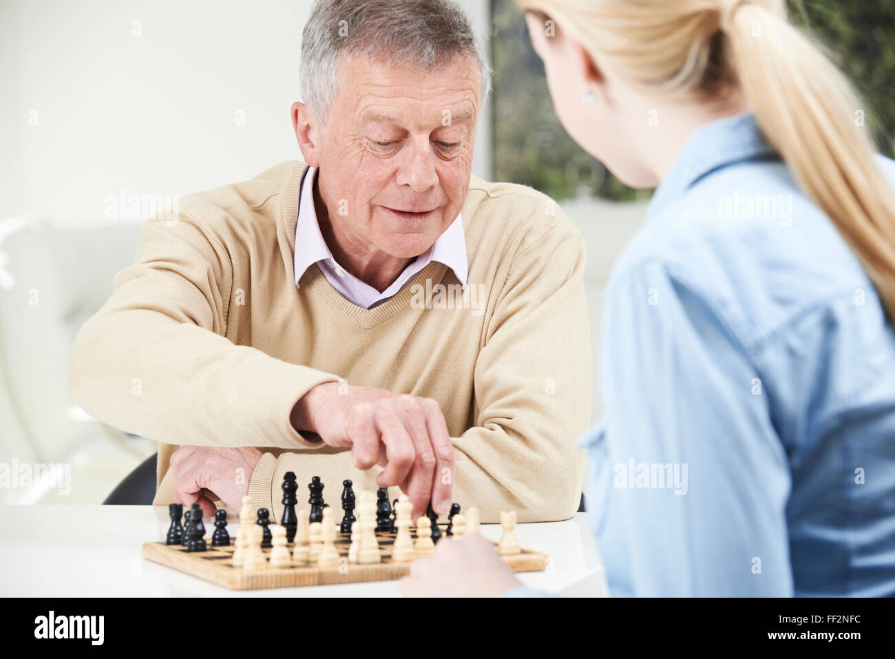 Senior Man Playing Chess With Teenage Granddaughter Stock Photo