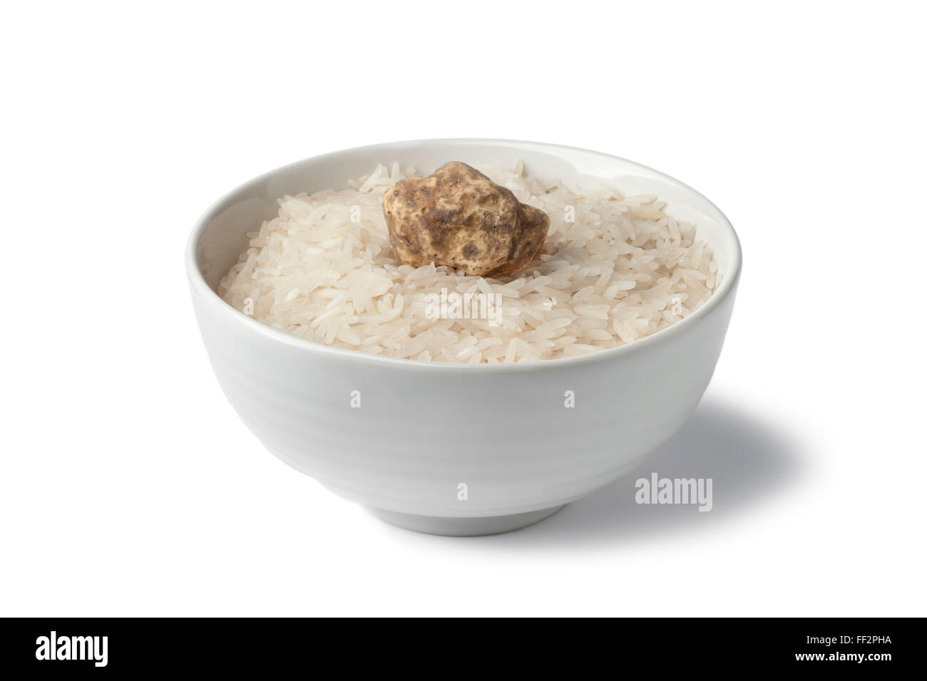 Cup of raw rice with fresh white truffle on white background Stock Photo