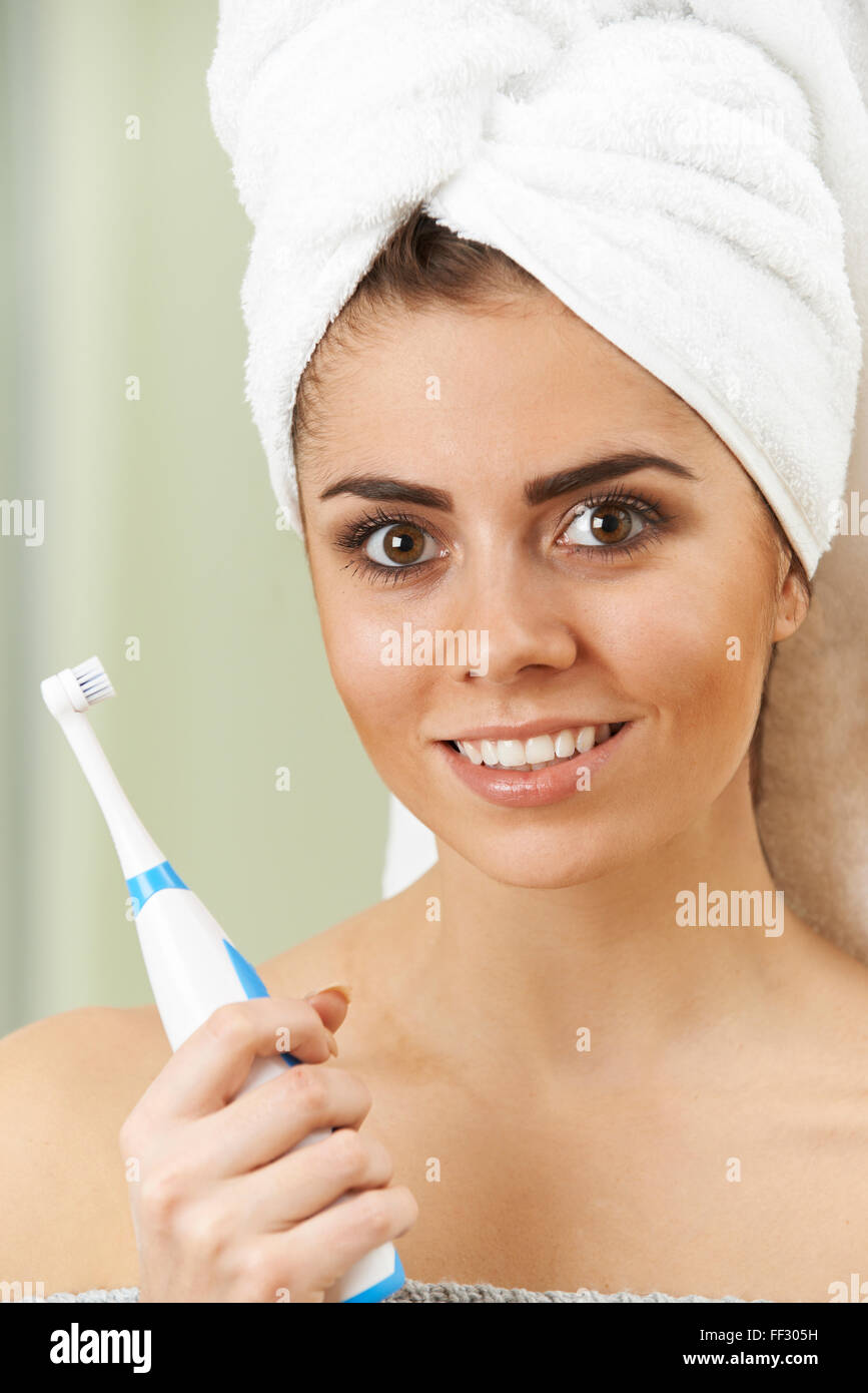 Woman Brushing Teeth With Electric Toothbrush In Bathroom Stock Photo