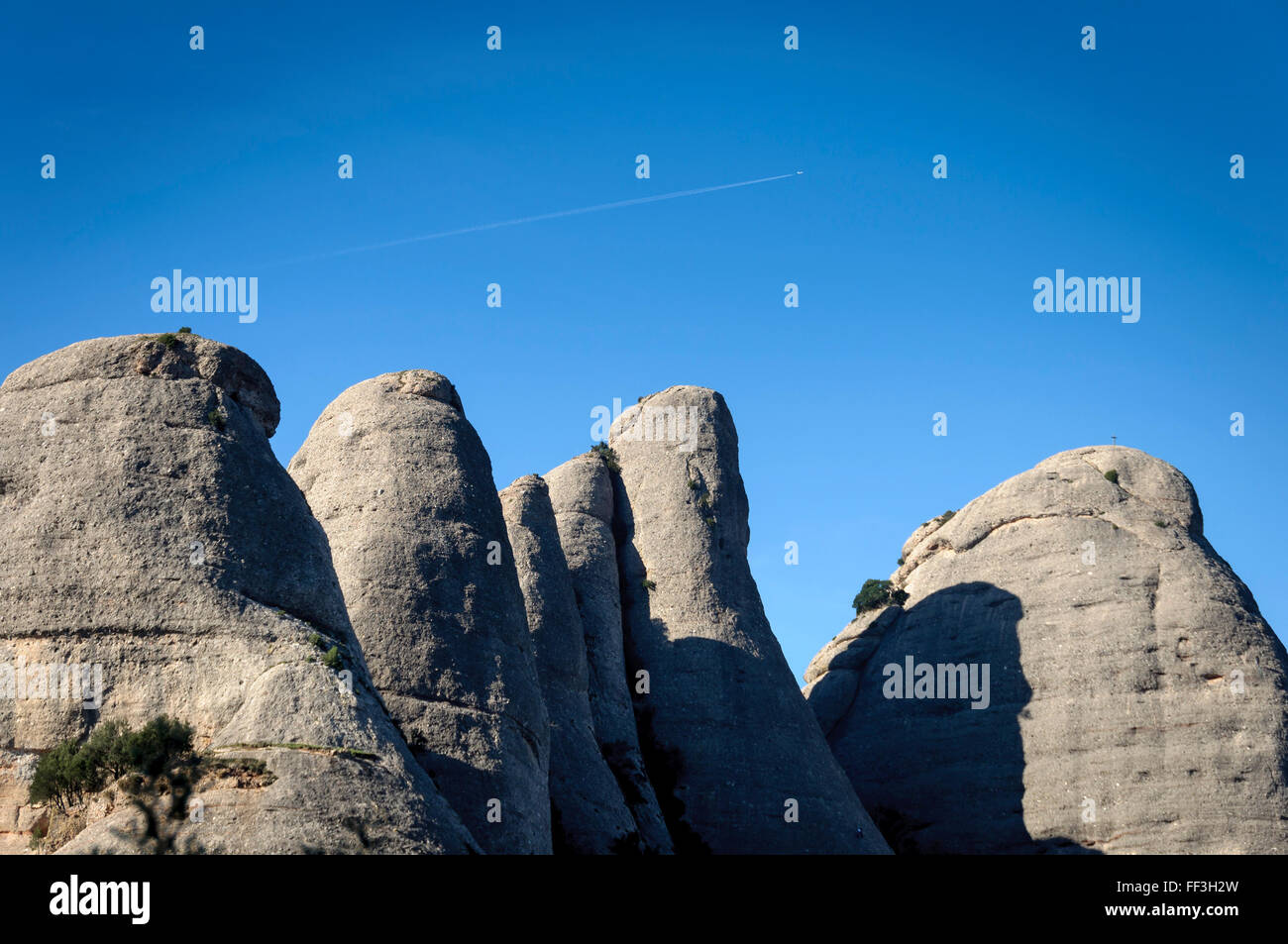 Trail of an airplane over the mountains of Montserrat , Barcelona, Catalonia , Spain Stock Photo