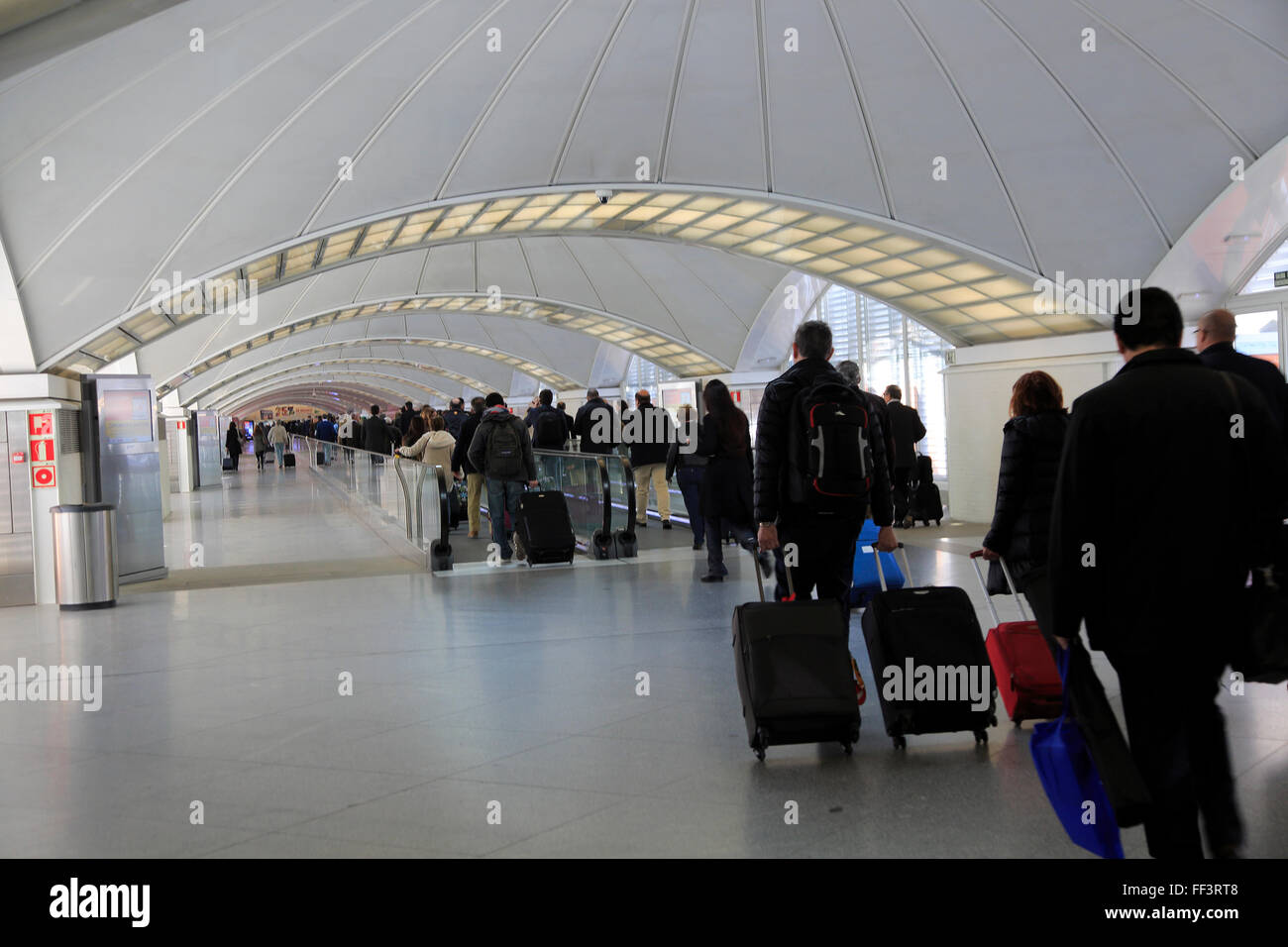 Passengers pulling luggage bags along a bright corridor, Atocha railway station, Madrid, Spain Stock Photo