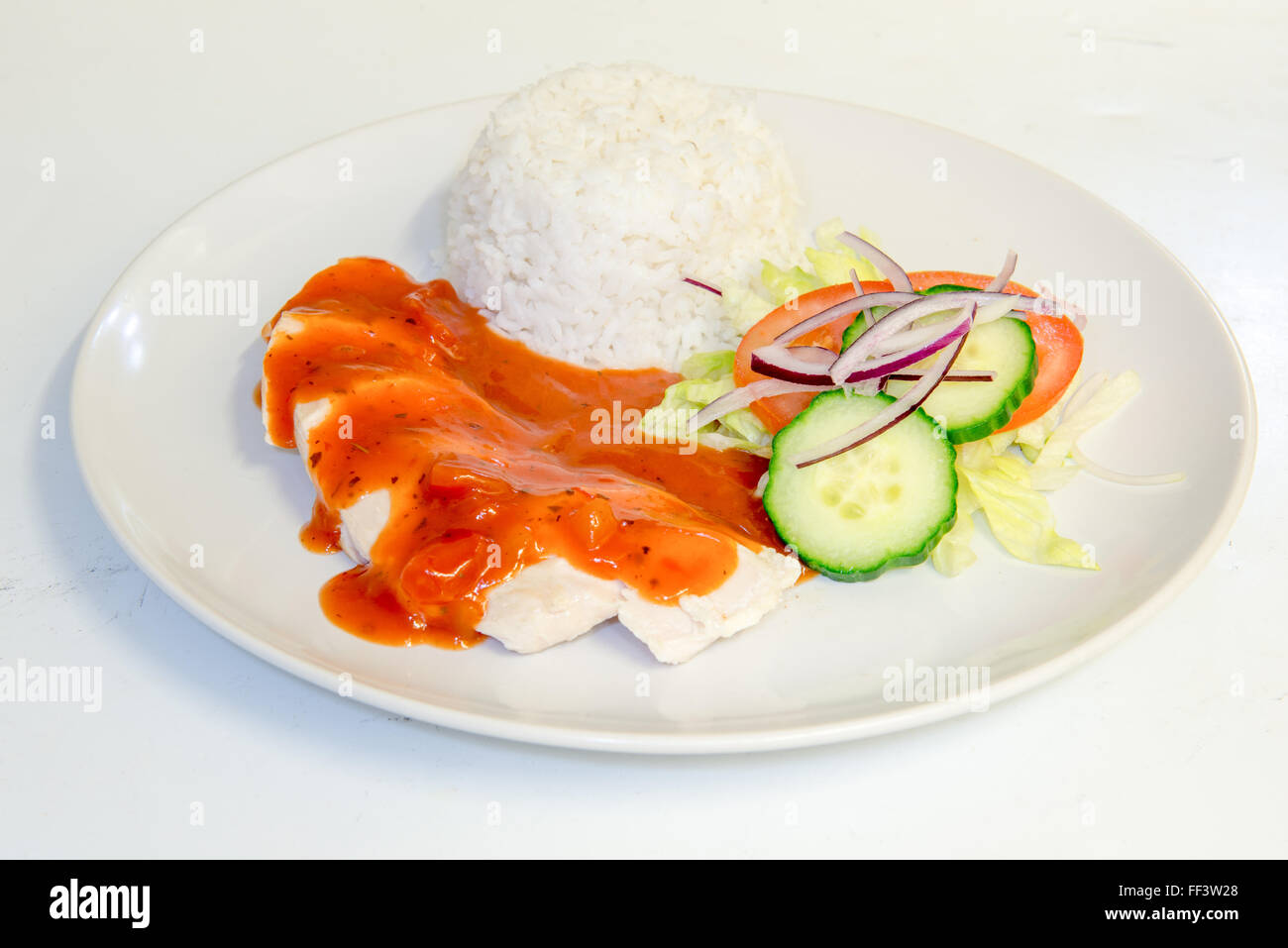 Chicken dinner with rice topped with tomato sauce Stock Photo