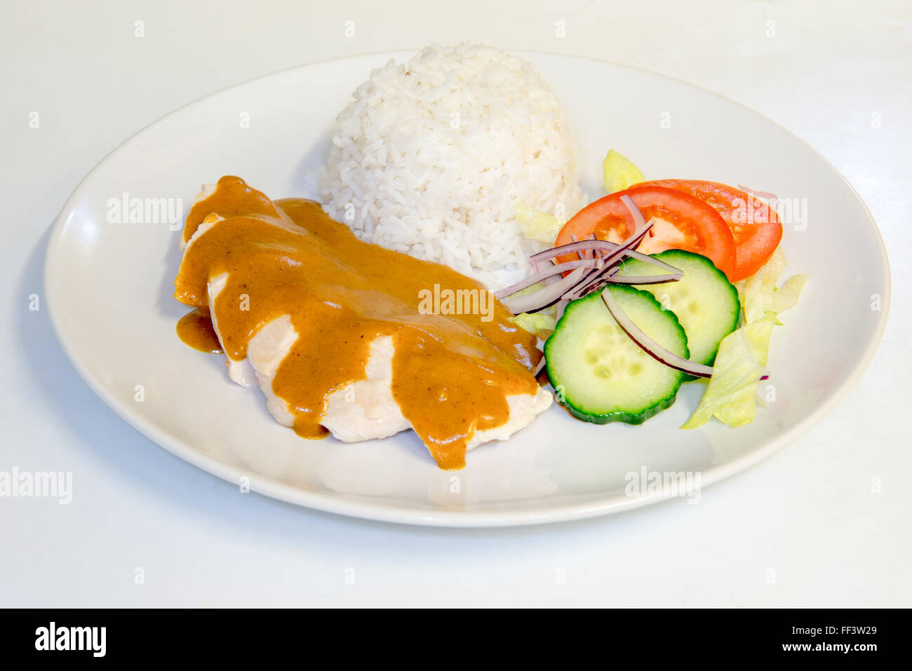 Chicken dinner with rice topped with curry sauce Stock Photo
