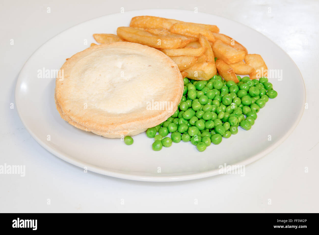 Pastry baked pie with chips and peas on a plate Stock Photo