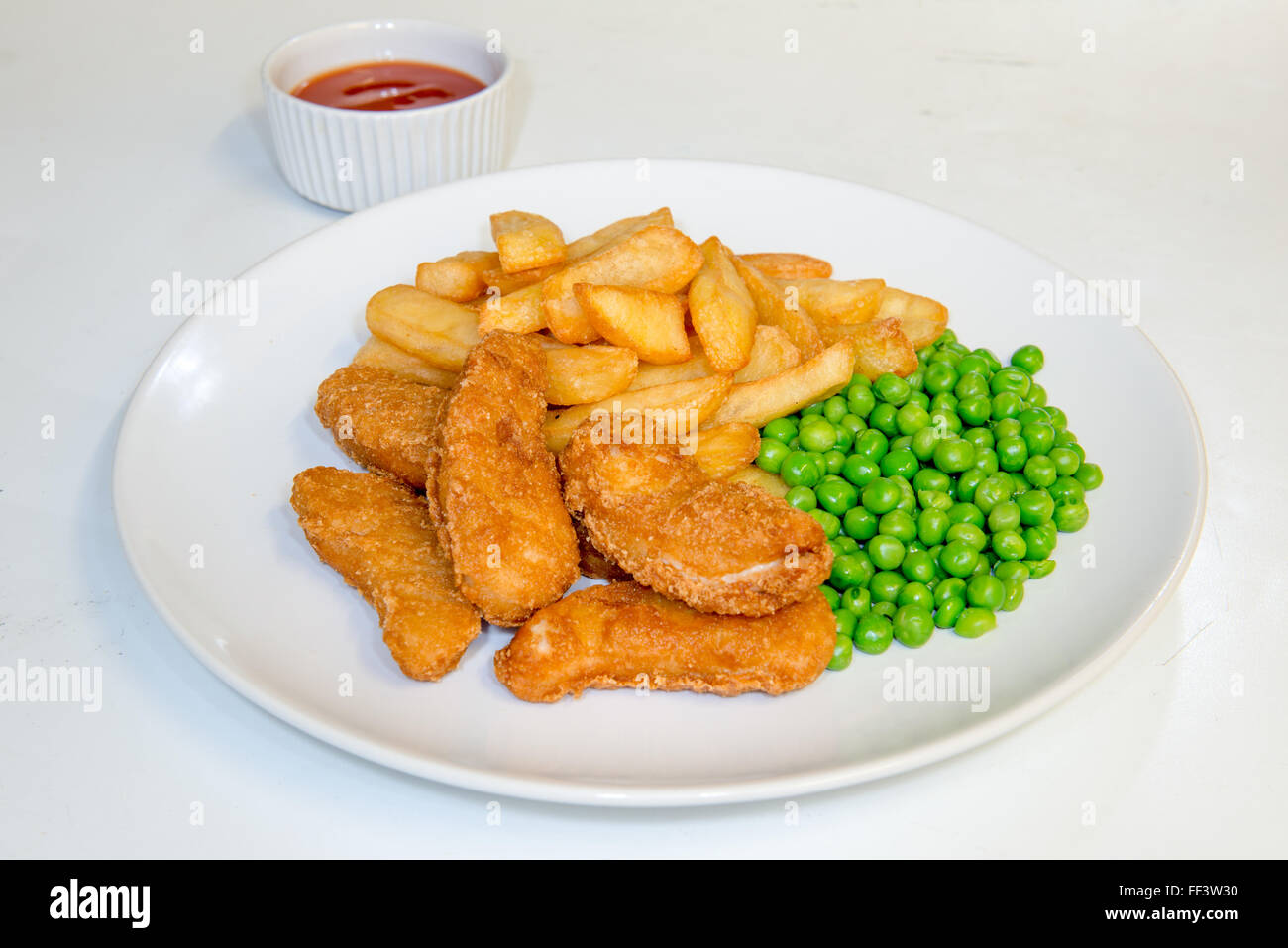 Chicken nuggets meal with chips, peas and tomato dipping sauce Stock Photo