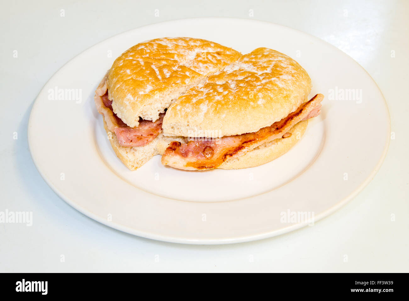 Small bread bun with bacon inside cut on a plate Stock Photo