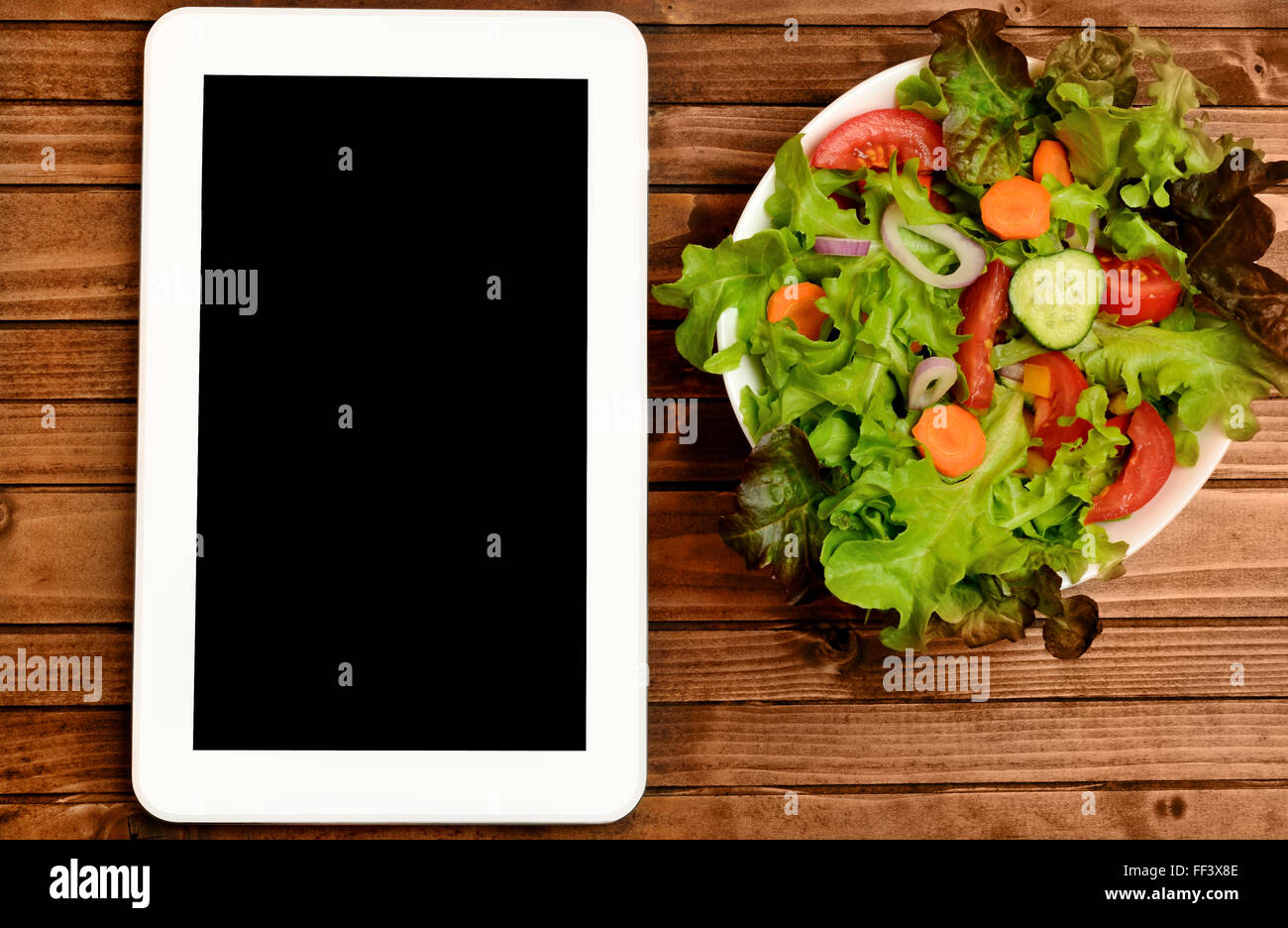 Tablet with vegetable salad on wooden table Stock Photo
