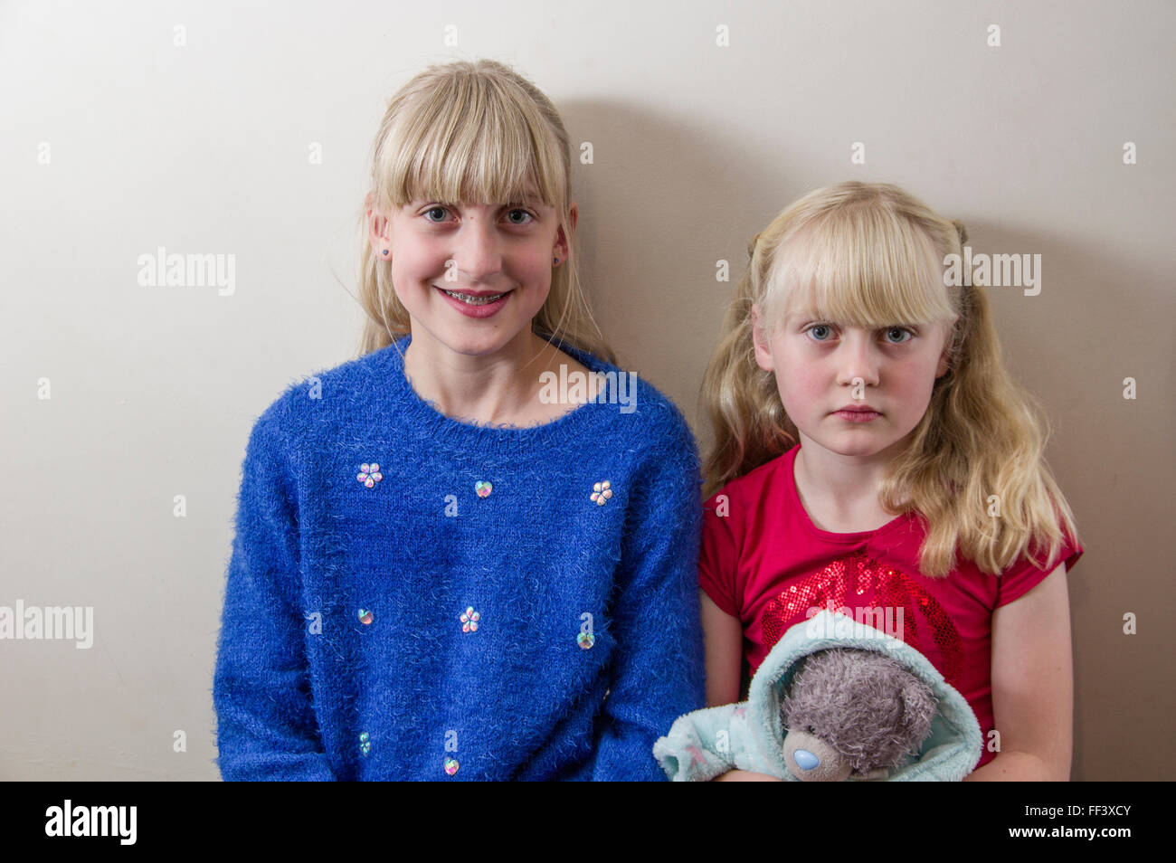 Studio portrait of two young, blond girls against a white background. Stock Photo