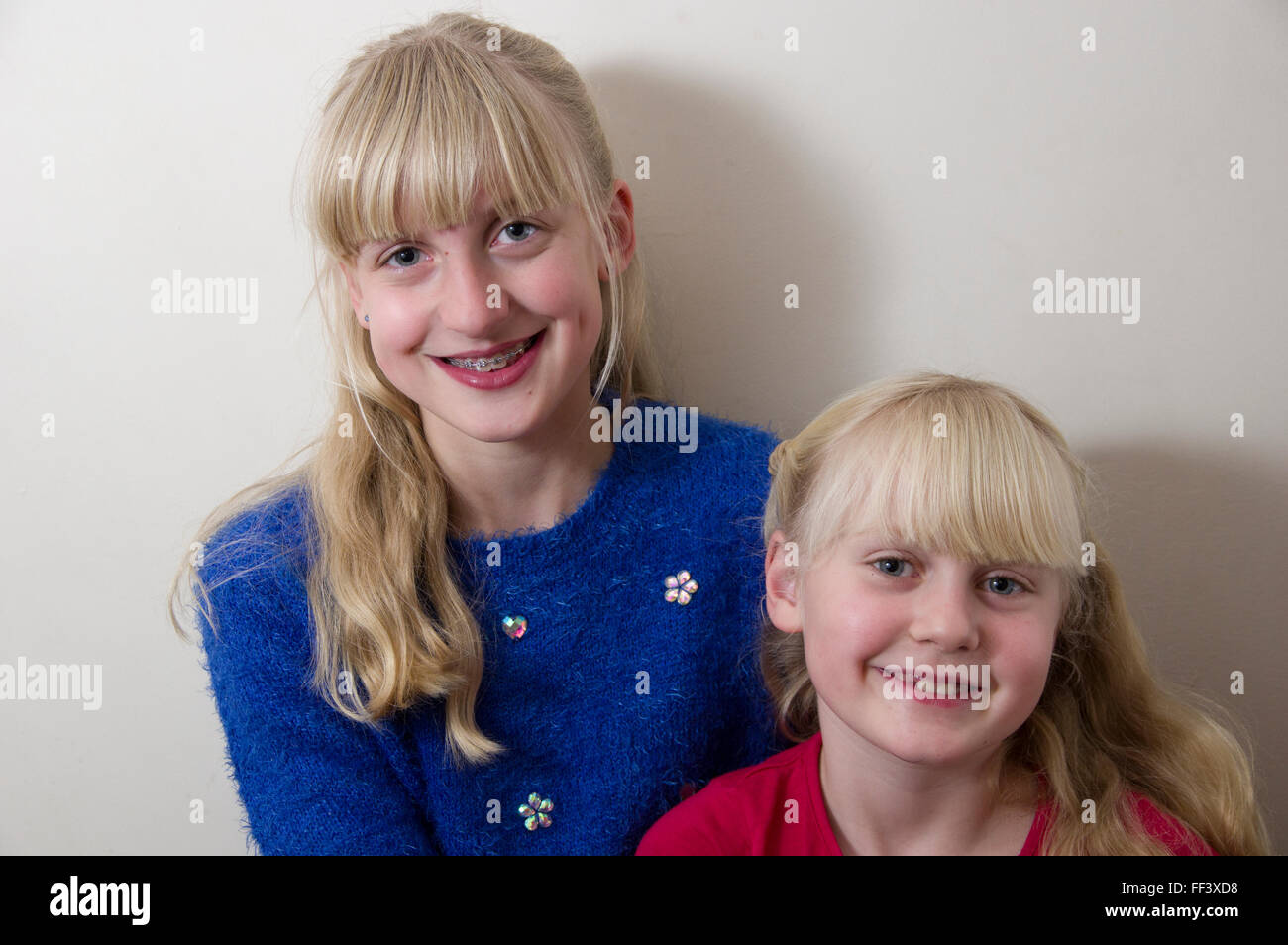 Studio portrait of two young, blond girls against a white background. Stock Photo