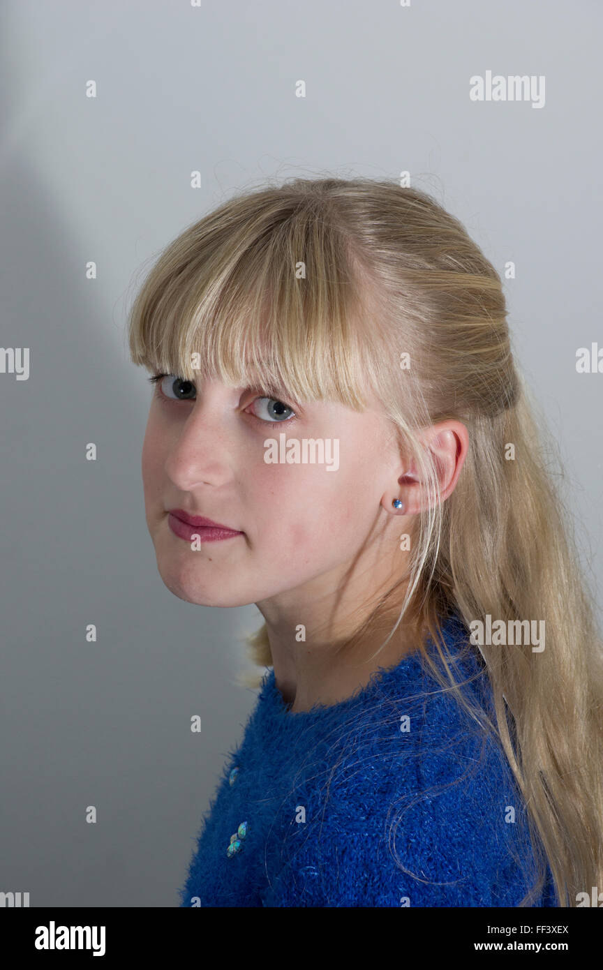 Studio portrait of a young, blond girl against a white background. Stock Photo