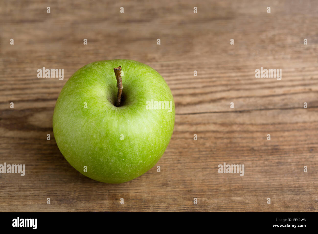 Green apple on wooden background, natural light Stock Photo