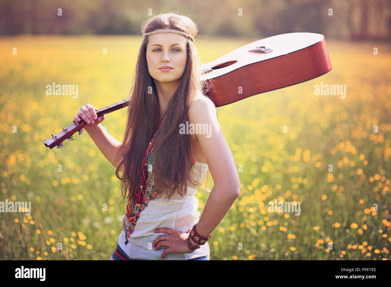 Beautiful hippie woman with guitar in a summer field. Peace and harmony Stock Photo