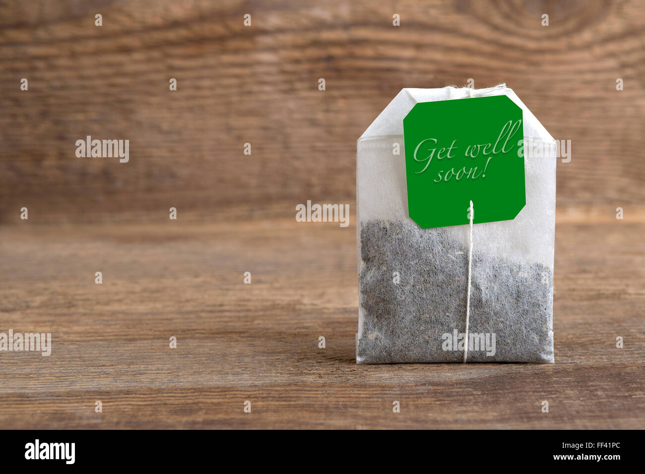 Closeup of green teabag on wooden background, get well soon Stock Photo