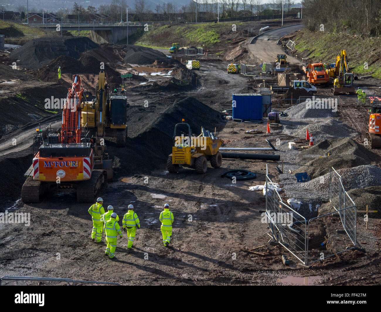 New road construction site, showing men working in safety gear, diggers and dump trucks. Stock Photo