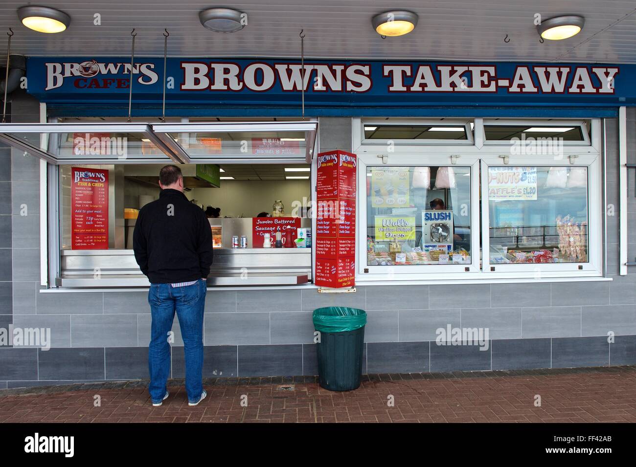 A customer stands at the service window of as Seaside Cafe in Cleethorpes in Lincolnshire to be served with a cup of tea Stock Photo