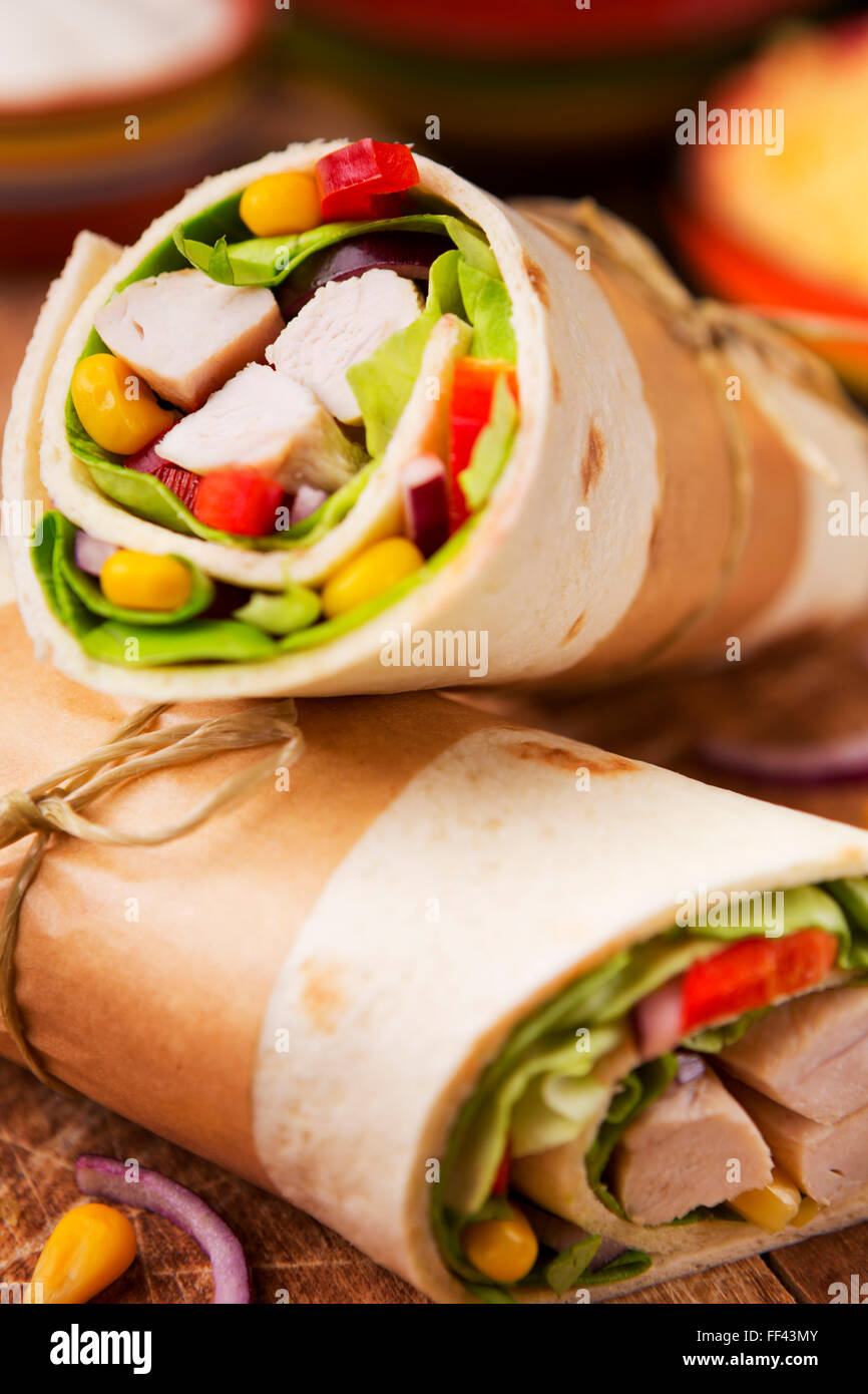 Healthy chicken wraps on a rustic chopping board. Stock Photo