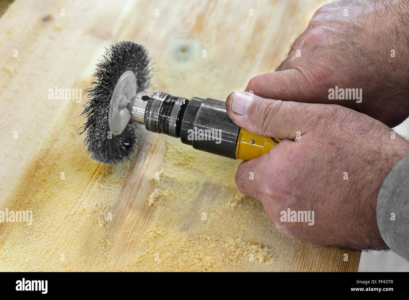 Hands man with electrical rotating brush metal disk sanding a piece of ...
