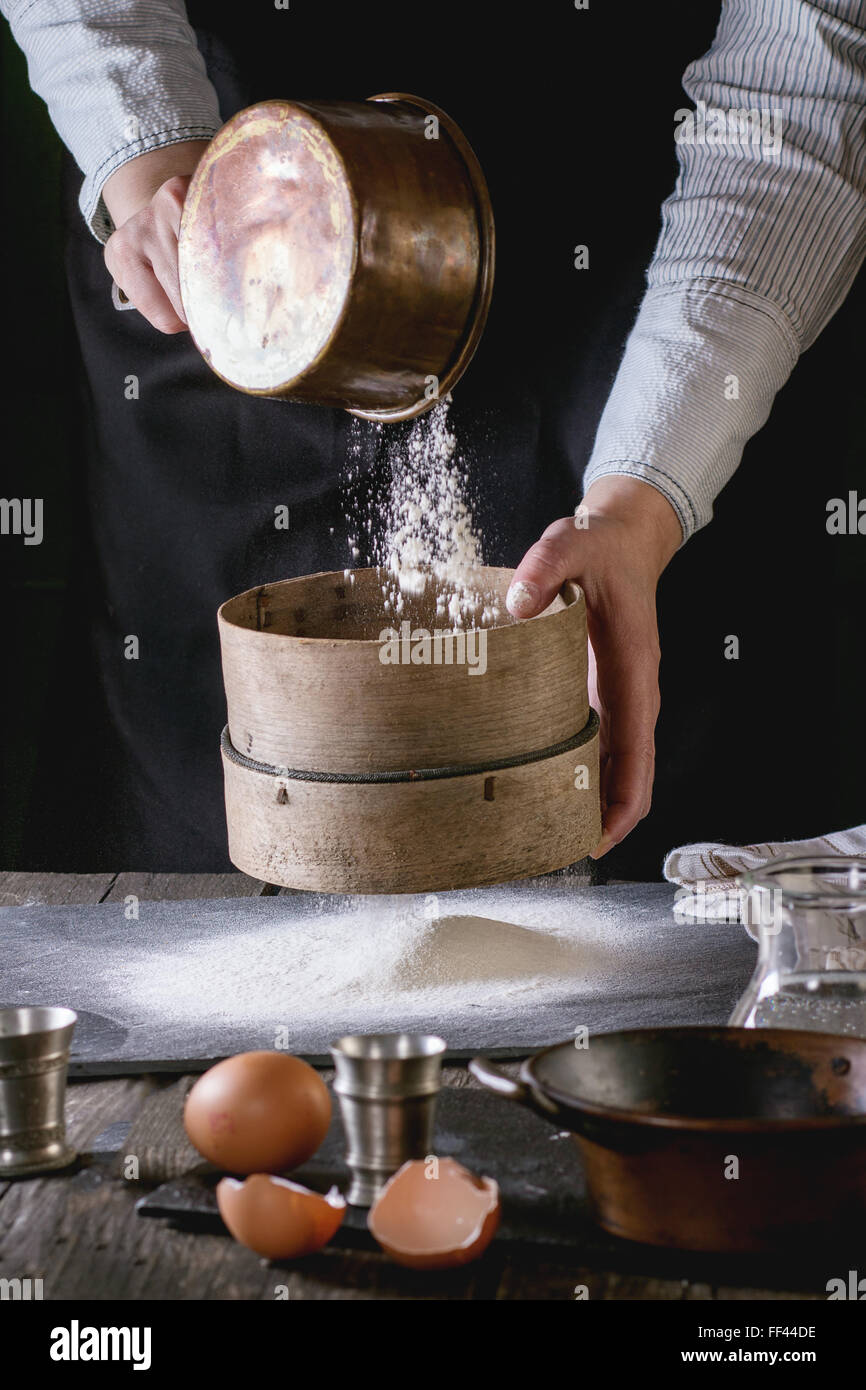 Sifting flour by female hands Stock Photo