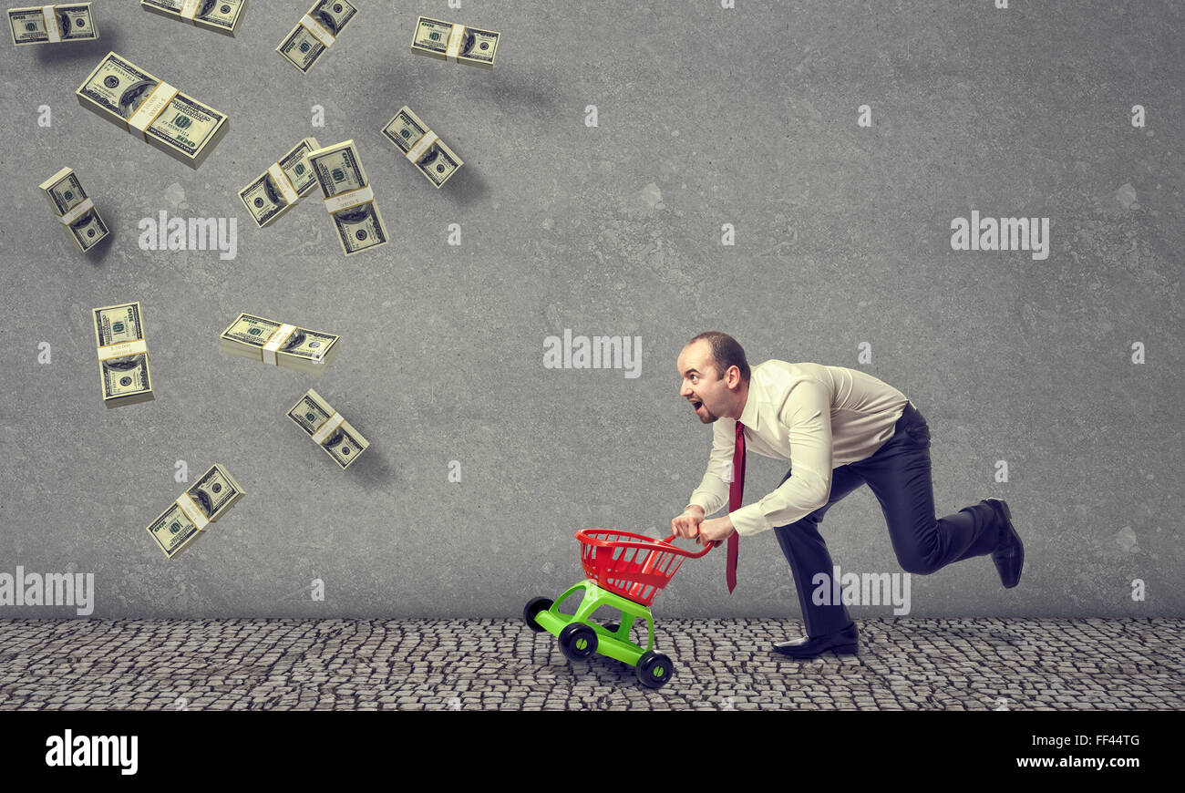 running man with shopping trolley and falling dollar Stock Photo