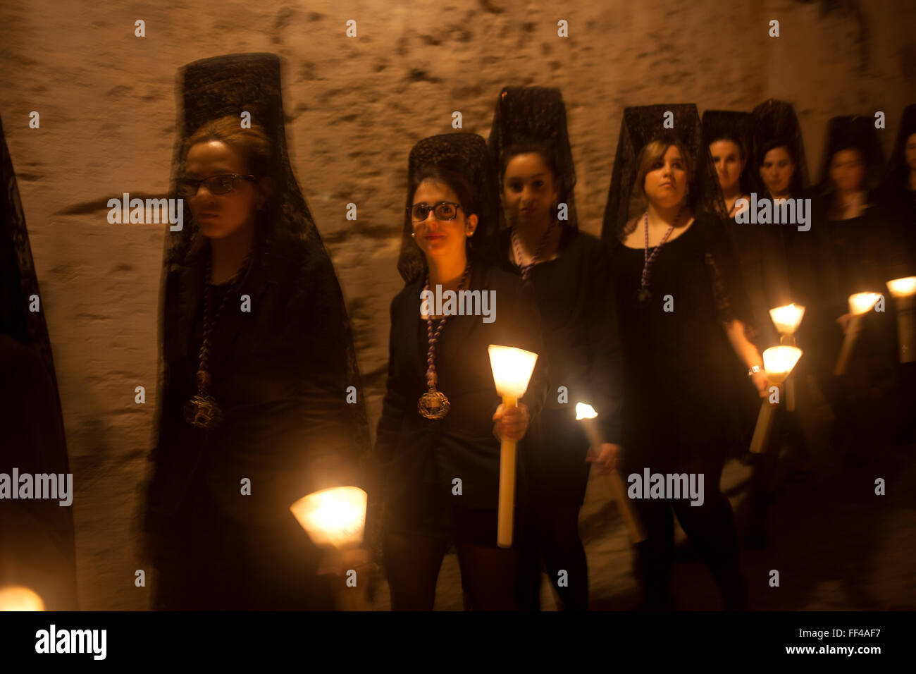 Women wearing mantillas hold candles during an Easter Holy Week