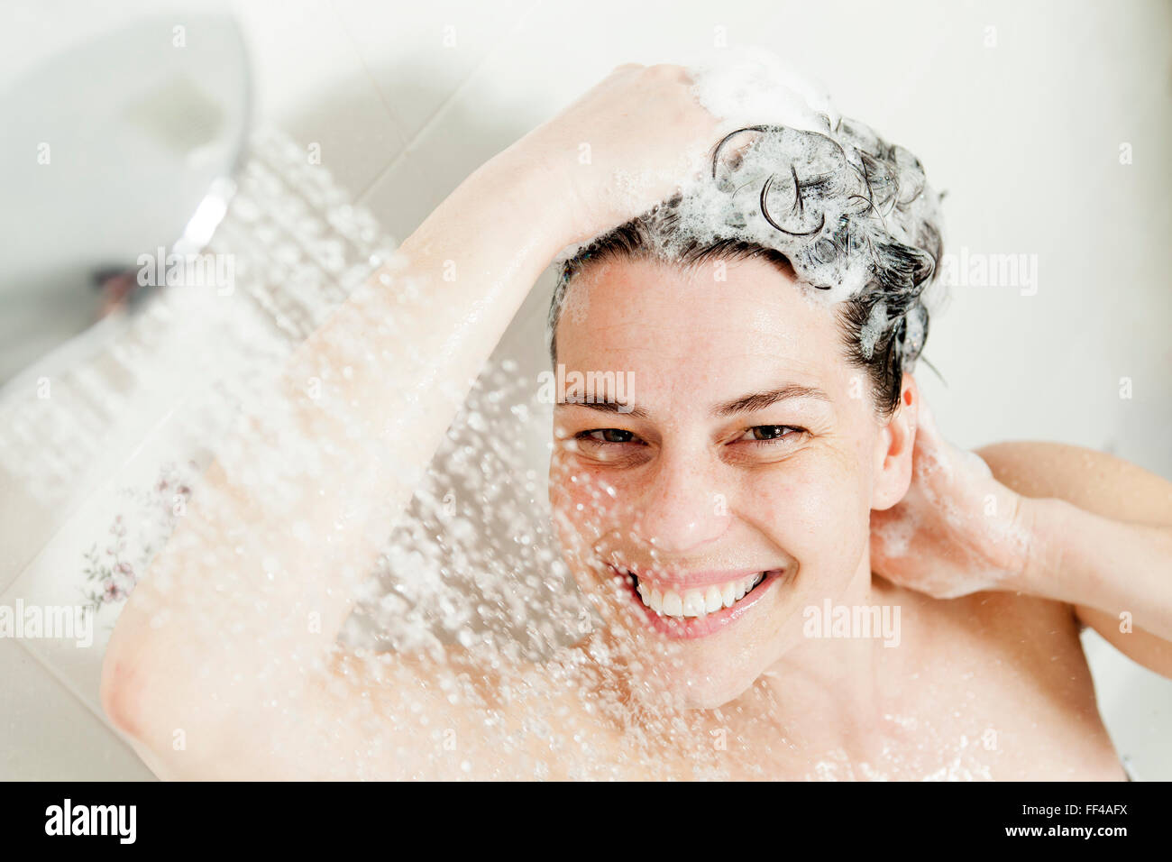 Shower woman. Happy smiling woman washing shoulder showering in Stock