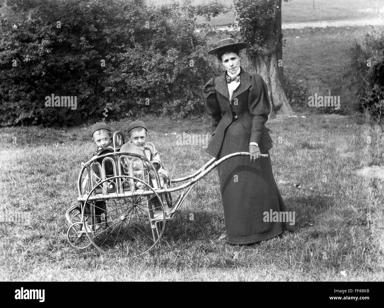 Victorian mother with twin children in pram pushchair Stock Photo