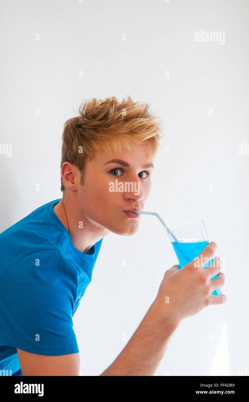 Young man drinking a blue isotonic drink, matching with his T-shirt. Close view. Stock Photo