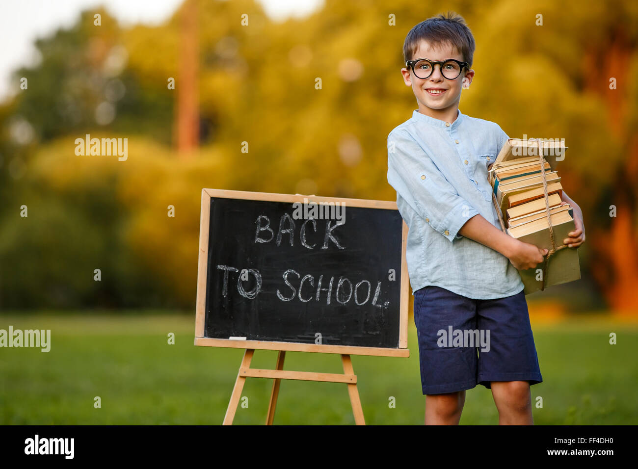 Cute little schoolboy carrying a stack of books Stock Photo