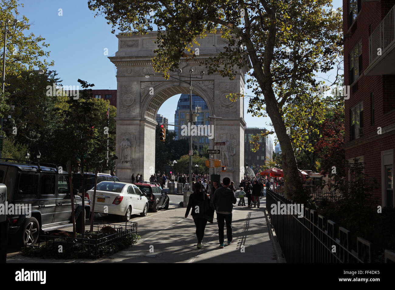 People walk south down Fifth Avenue into Washington Square Park on a warm autumn day Stock Photo