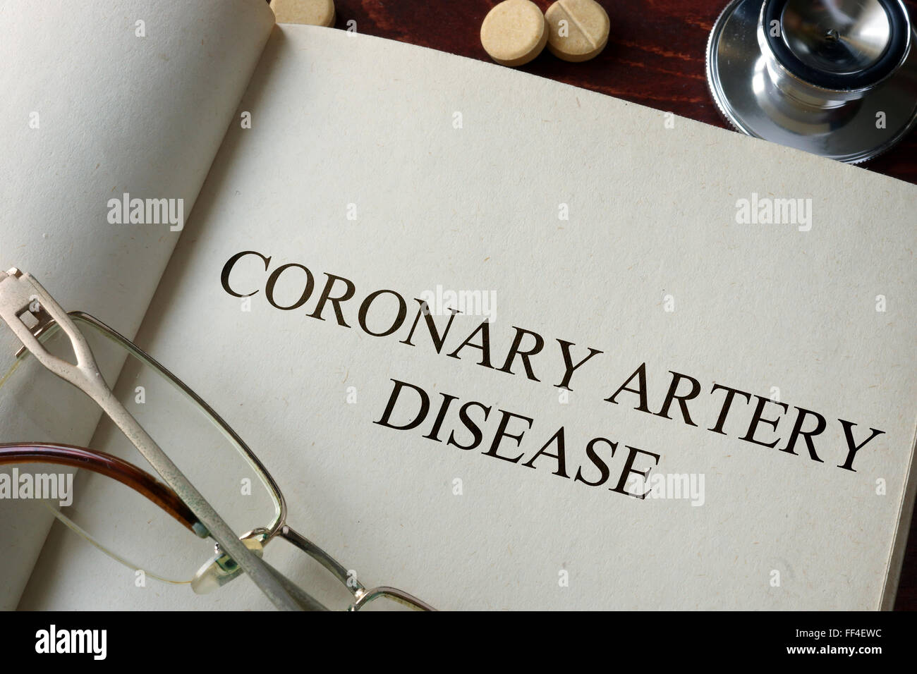 Book with diagnosis coronary artery disease and pills. Medical concept. Stock Photo