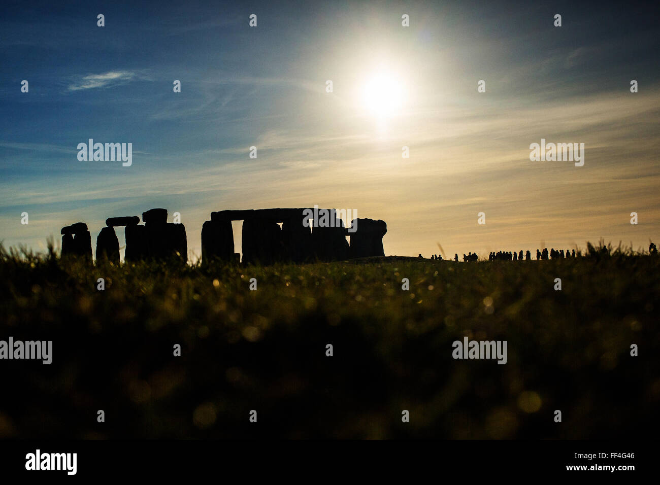 Stonehenge in silhouette with midday sun in blue sky Stock Photo