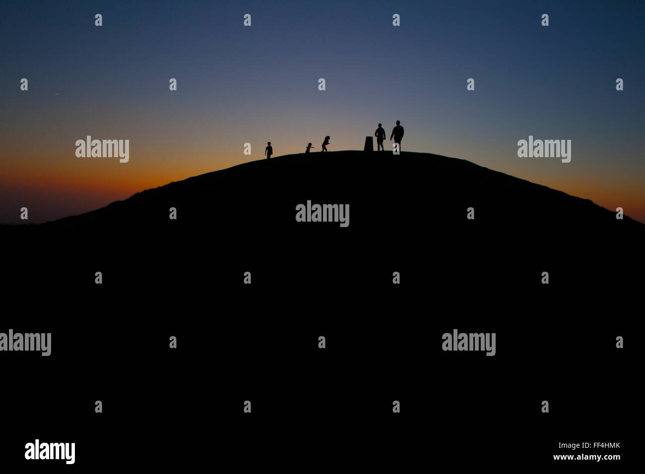 Silhouetted figures on the peak of the Garth Mountain at sunset. Stock Photo