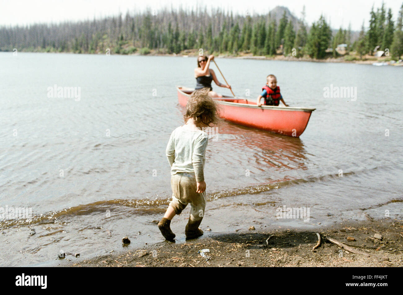 Mom with two young kids and a canoe at Big Lake in Oregon. One of the children is very dirty from the sand and the other child i Stock Photo