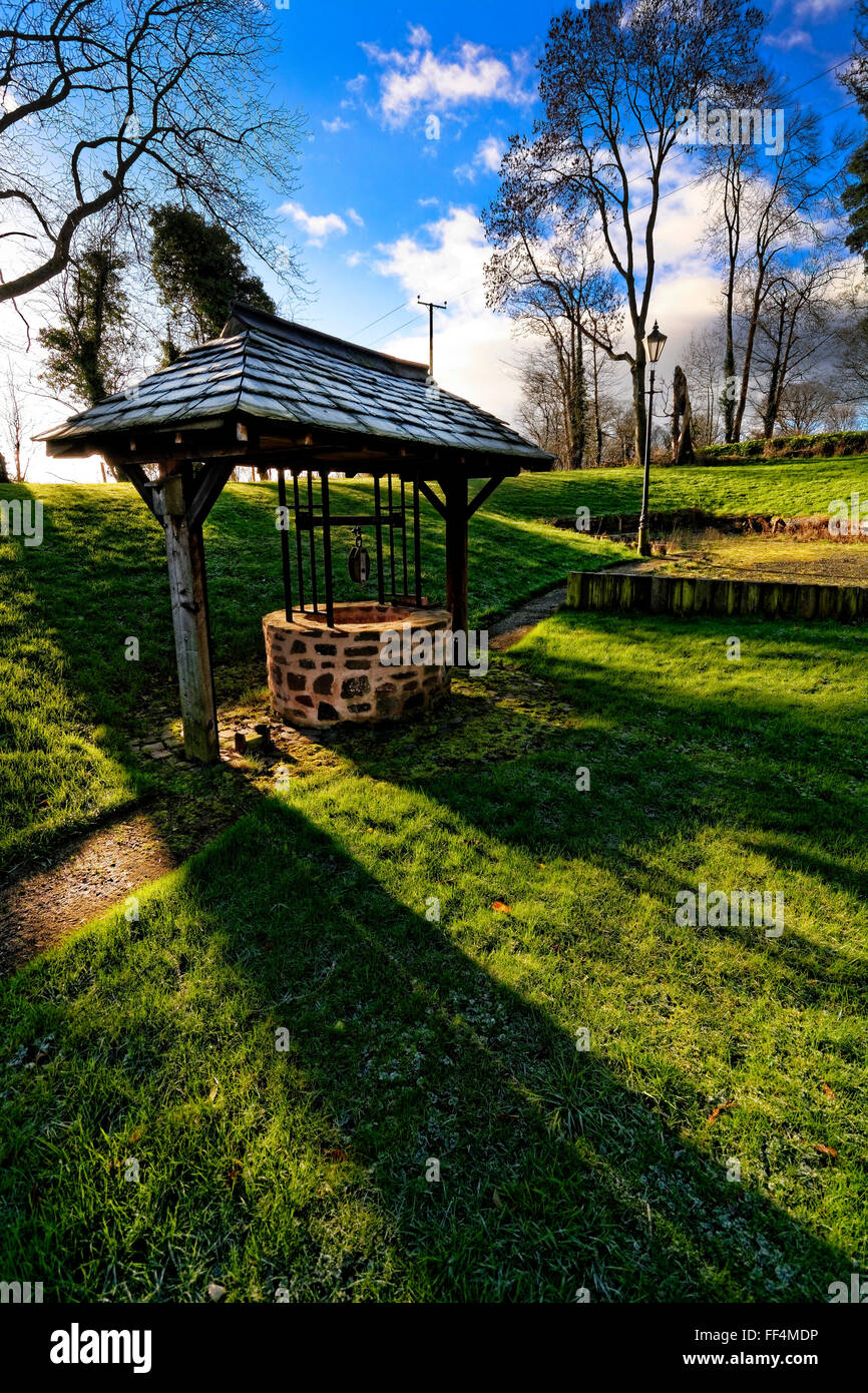 Shadows cross a well that is an attractive and valuable garden element Stock Photo