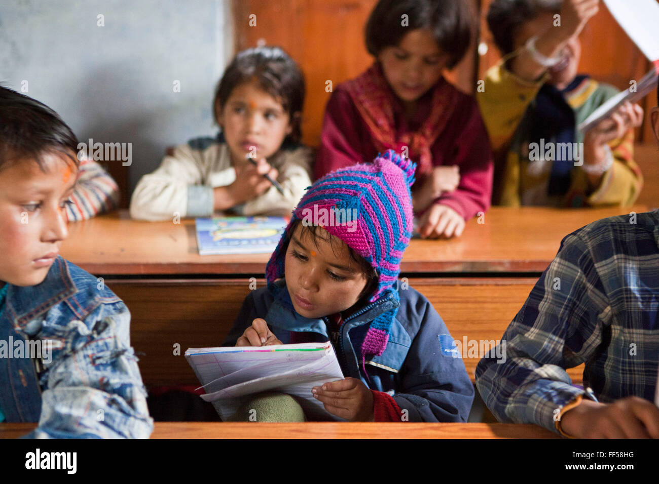 A young boy writing during a lesson at the Alternate Learning Hub, Subhai, Himalayas, India. The school is organized and funded by the Pragya charity.  Pragya is a non-profit organization providing education and information services in high altitude areas in the Himalayas. Stock Photo