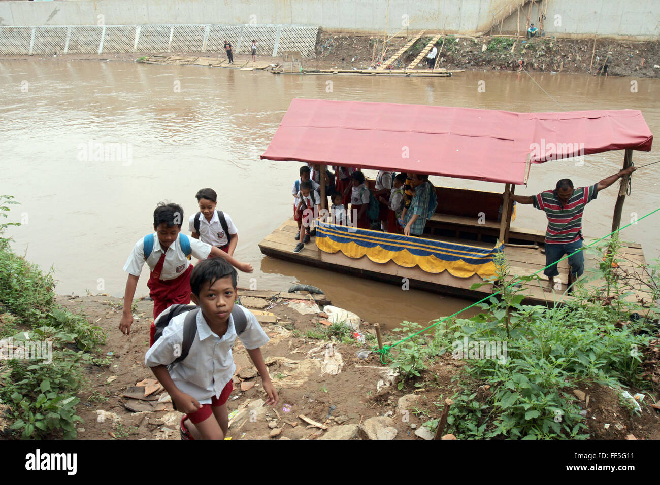 School children ride a boat to cross the Ciliwung River. Education in ...