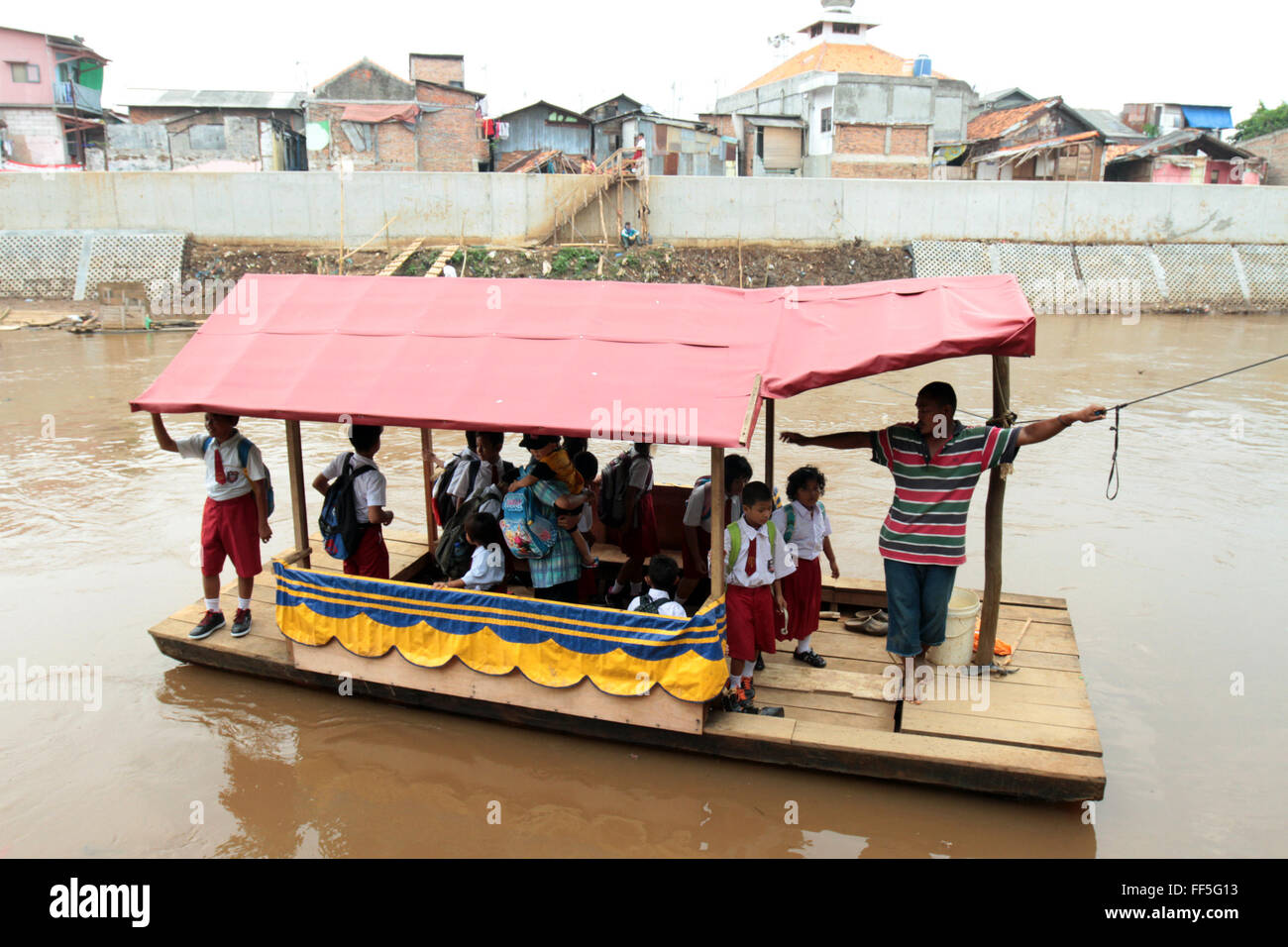 School children ride a boat to cross the Ciliwung River. Education in
