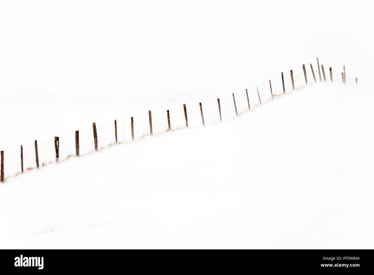 Minimalist image of fence going up hillside in the snow at Iceland in January - minimalist landscape scenery scenic - snow minimalism Stock Photo