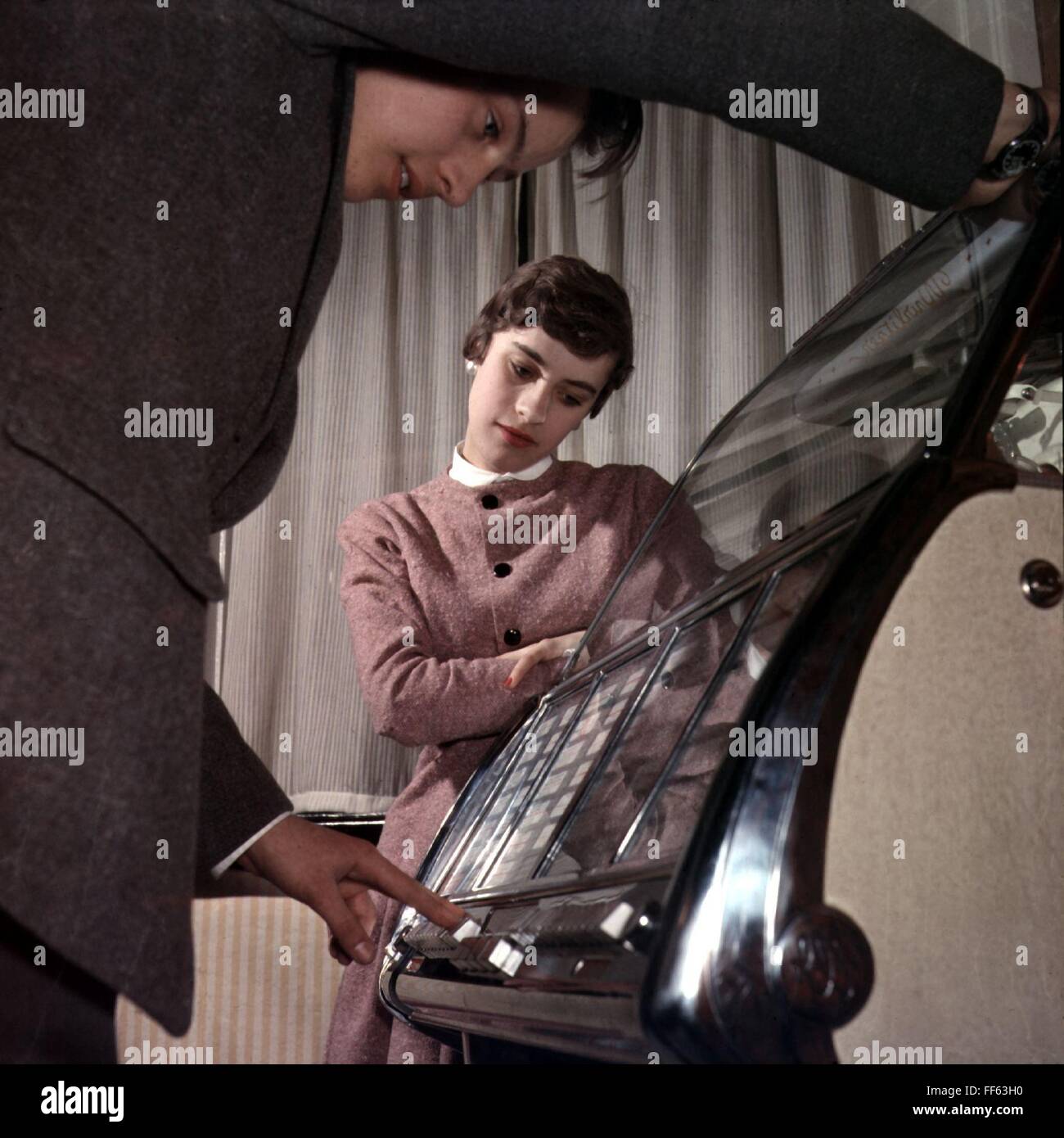 music, music box, woman looking at his boyfriend operating a jukebox, 1950s, , Additional-Rights-Clearences-Not Available Stock Photo