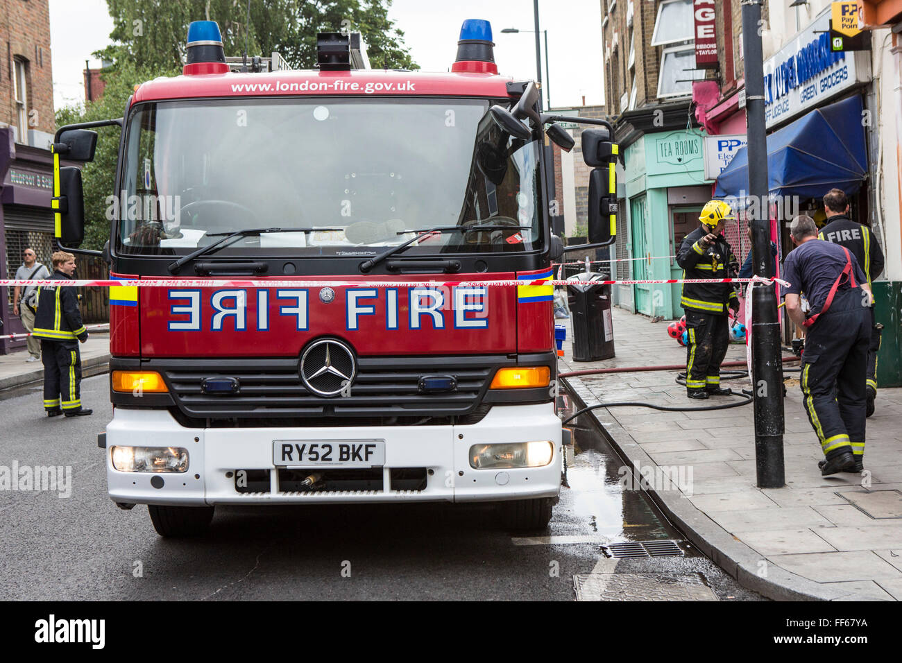 A London Fire Brigade unit responding to an emergency on Church Street, Stoke Newington, London, United Kingdom.  Firefighters have seal off the area with barricade tape to ensure public safety while they work. Stock Photo